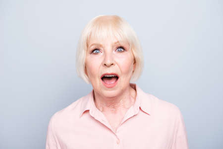 Old lady amazed shocked wow facial expression on grey backgroundの写真素材