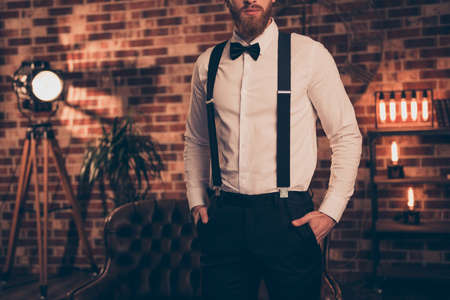Vintage wealthy style classic chic posh party loft concept. Cropped close up photo of stylish trendy virile masculine chief keeping hands in pockets standing over brown brick backgroundの写真素材
