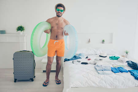 Full length size body portrait of attractive handsome young bearded smiling man in bedroom, carrying...