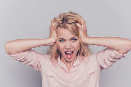 Young lovely blonde caucasian curly-haired nice pretty stressed woman yelling screaming crying. Isolated over grey backgroundの写真素材