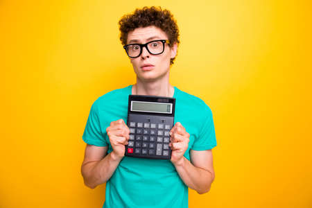 Attractive curly-haired young guy student, wearing casual green t-shirt, showing zero on calculator....