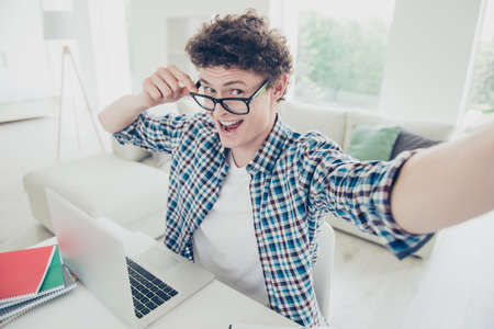 Handsome curly-haired excited young guy student at home, wearing casual, glasses, studying learning...