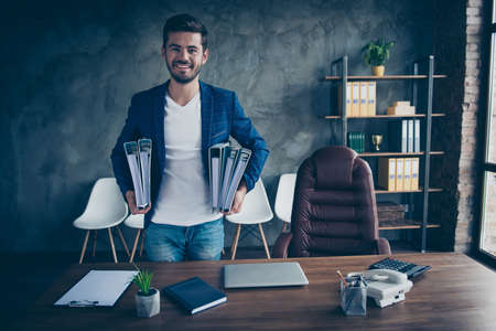 Confident man happily looks into the camera holding a folder of papers, which he prepared for the...