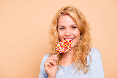 Close up photo portrait of pretty cheerful joyful lady tasting sweet colorful candy on stick in hand isolated on bright vivid color background copy spaceの写真素材