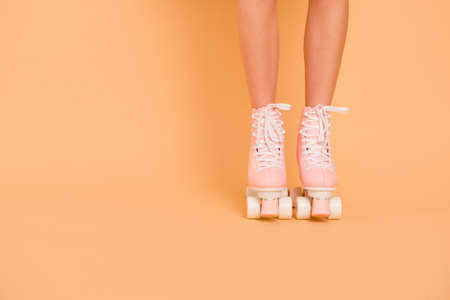 Crop photo of legs in vintage quad roller skates shoes isolated on pastel peach background with copy space for textの写真素材