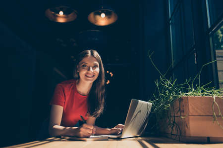 Attractive nice smiling dreamy young girl freelancer student wearing casual sitting in cafeteria,...