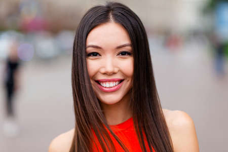 Ð¡lose up portrait of charming young girl with lovely toothy smile looking at camera against a blurred background of cityscapeの写真素材