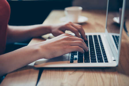 Crop photo of hands of a young girl who type a message on the laptop keyboardの写真素材