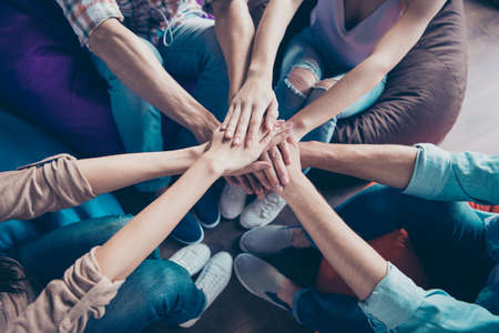 Concept of support. High angle top view and close up photo of hands stacked on top of each other...