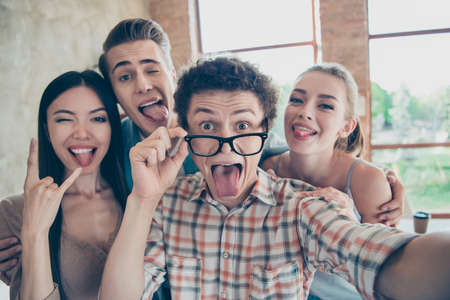 Self-portrait of four cheerful glad people, guys and girls having rest, pause, break at work,...