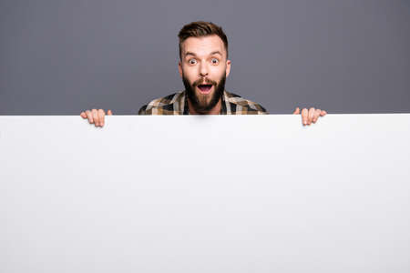 Cheerful surprised and beautiful man standing behind the white b