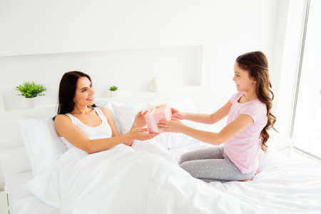 Nice sweet tender small little daughter in nightwear giving pinkの写真素材