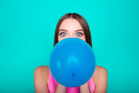 Portrait of young lovely nice sweet girl lady blowing big blue aの写真素材