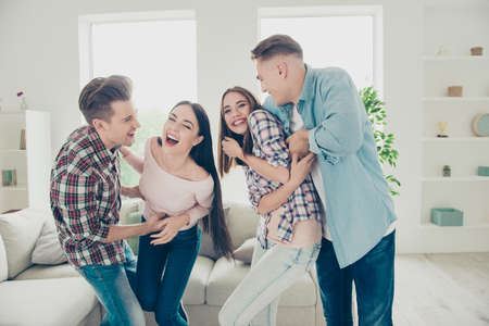 Careless, cheerful hipster guys tickle the girls in street style