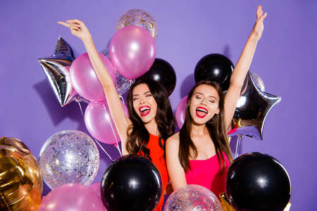 Two young woman in casual outfit close eyes raised hands up loud