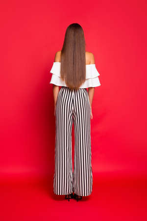 Portrait of back view woman with red background.