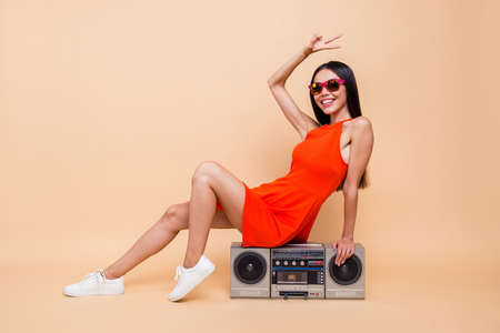Clubber club sound trendy people person she her concept. Full length body size photo of carefree pretty beautiful attractive lady make give v-sign sitting on stereo player isolated beige backgroundの写真素材