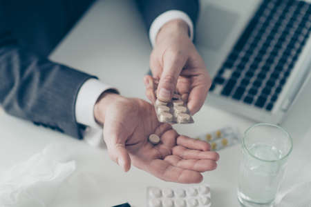 Close up cropped photo of man hands with pill packaging he hold blister sit in formal wear on white workstationの写真素材