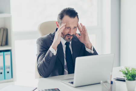 Half turn advocate agent analyst banker broker brunet hair stubble worried man in formal wear look on pc gadget screen monitor sit on chair armchair behind table in workplaceの写真素材