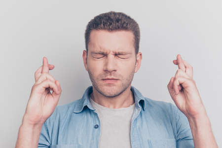 Close up portrait of close eyes man cross fingers on two hands want plan best result for himself...