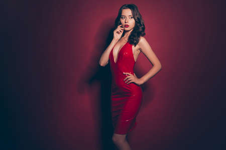 Good-looking confident lady with modern hairstyle dressed up in a red latex dressの写真素材