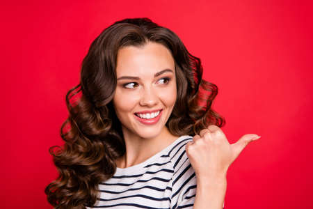 Close up portrait of glad attractive beautiful pretty she her girl with thumb raised to empty space look like good job isolated on red vivid bright backgroundの写真素材