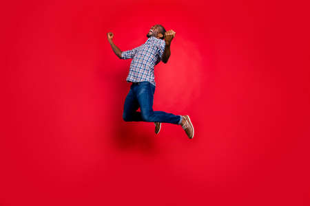Full length body size portrait of nice funny glad handsome cheerful positive trendy guy wearing checkered shirt showing winning gesture cool party in air isolated on bright vivid shine red backgroundの写真素材