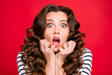 Close up portrait of attractive oops oh no looking she her girl full of fear watching horror movie white striped pullover isolated on red vivid backgroundの写真素材