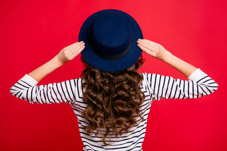 Rear back behind view of nice well-groomed gorgeous attractive wavy-haired lady wearing striped pullover sunhat isolated over bright vivid shine red backgroundの写真素材