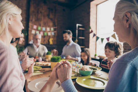 A big family recite prayers before eating lunch at the tableの写真素材