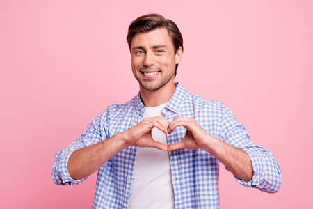 Portrait of his he nice attractive handsome cheerful cheery positive guy wearing checked shirt showing heart shape isolated over pink pastel backgroundの写真素材