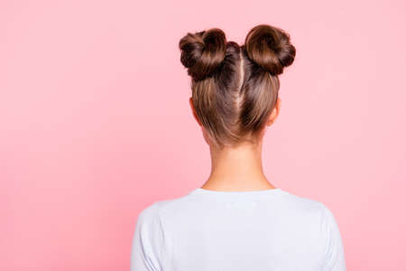 Rear back behind view of nice attractive groomed girl wearing two fashionable buns isolated over pink pastel backgroundの写真素材