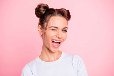 Close-up portrait of her she nice cute lovely attractive winsome cheerful cheery girl with buns winking opened mouth isolated over pink pastel backgroundの写真素材