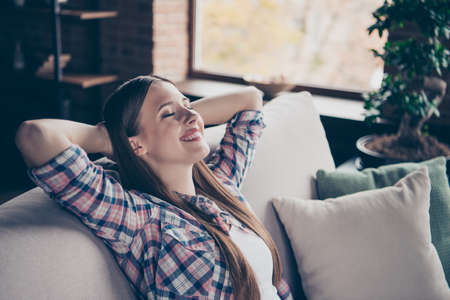Side profile close-up photo portrait of beautiful charming glad calm with straight long brown hairstyle wearing plaid outfit holding hands behind headの写真素材