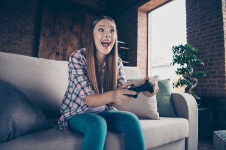 Low angle view photo portrait of cheerful ecstatic excited enthusiastic she her hipster teen girl using holding controller in hands playing wireless computer videogamesの写真素材