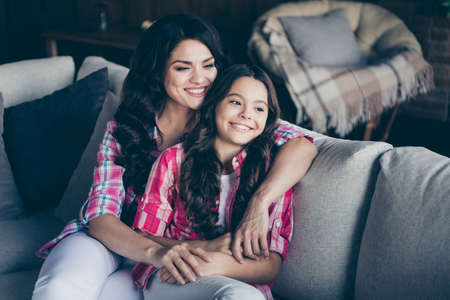 Portrait of two nice stylish trendy sweet attractive lovely stunning winsome cheerful wavy-haired girls sisters sitting on divan in modern loft industrial interiorの写真素材