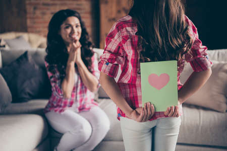 Close up back behind rear view photo two people mum little daughter giving postcard holiday morning sweet unexpected cute delighted wear pink plaid shirts flat apartment room sit cozy couch sofa divanの写真素材