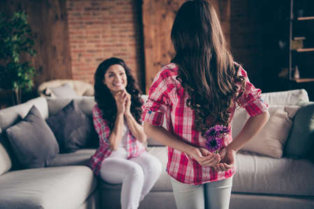 Close up back behind rear view photo two people mum little daughter give bouquet holiday morning sweet unexpected cute delighted wear pink plaid shirts flat apartment room sit cozy couch sofa divanの写真素材