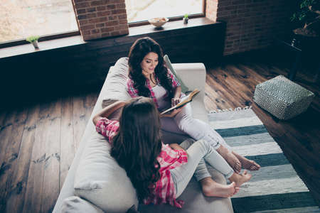 High angle view of nice lovely adorable winsome attractive charming cheerful cheery dreamy wavy-haired people mom reading book free time in house indoorsの写真素材