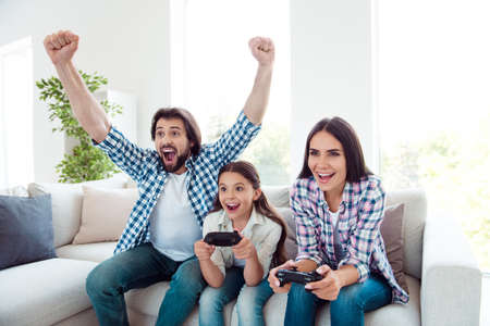 Portrait of nice cute adorable attractive cheerful cheery positive funny people mom dad spending free spare time competition contest in light white modern interior indoorsの写真素材