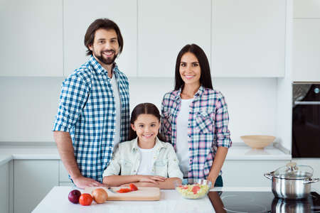 Portrait of nice lovely lovable adorable attractive cheerful cheery people mommy daddy pre-teen kid making fresh useful salad dish in light white interior roomの写真素材
