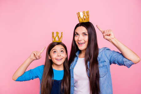 Portrait of two nice cute pretty lovely attractive cheerful cheery positive glad amazed straight-haired girls wearing pointing forefinger at luxury crown win winner ego isolated over pink backgroundの写真素材
