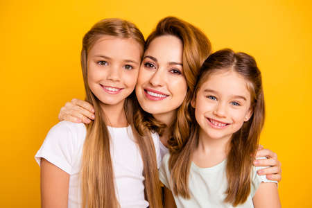 Close-up portrait of three nice cute adorable attractive healthy cheerful caucasian people cuddling mum mommy isolated over bright vivid shine yellow backgroundの写真素材