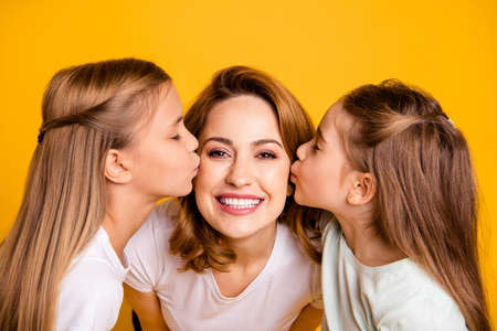 Close-up portrait of three nice cute adorable winsome lovely sweet tender attractive cheerful cheery positive people kissing mum having fun feelings isolated over bright vivid shine yellow backgroundの写真素材