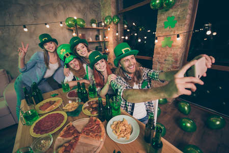 Nice cool attractive lovely stylish trendy cheerful cheery glad positive group of people guy taking making selfie on phone having fun festive night life showing v-sign indoorsの写真素材