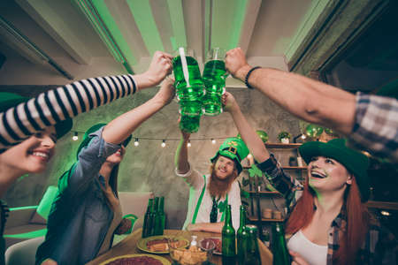 Low below angle view of nice attractive lovely stylish cheerful cheery optimistic positive group of people guys gathering union having fun clinking jar mug over served table congrats in house pub indoorsの写真素材