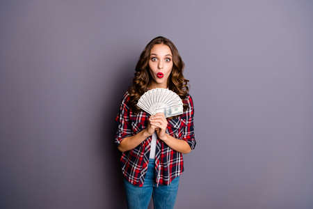 Close up portrait of beautiful amazing wondered she her lady hands hold big sum of money eyes mouth open do not believe wearing casual checkered shirt isolated grey backgroundの写真素材
