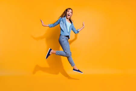 Full length body size photo yelling  jumping high beautiful she her lady little low prices announce black friday shopping store wearing casual jeans denim shirt clothes isolated on yellow backgroundの写真素材