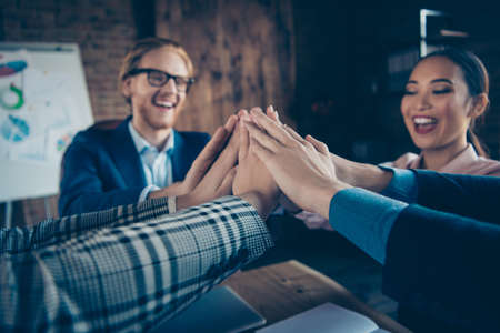 Cropped close-up view of nice chic elegant stylish cheerful glad business sharks experts gathering putting palms over desktop desk table at modern industrial loft interior work place stationの写真素材