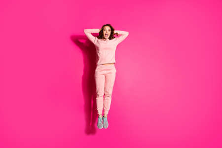 Full length body size photo jump high amazing she her lady hands arms behind head unbelievable success shopping wearing casual pink costume suit pullover outfit isolated vibrant rose backgroundの写真素材